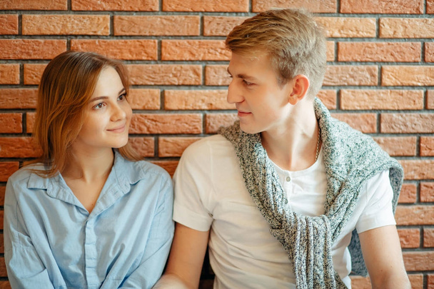 Couple Smiling at Each Other Against Brick Wall Background. - Foto, immagini
