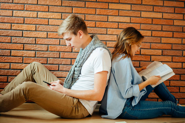 young couple reading a book sitting on wooden floor at home - Foto, immagini