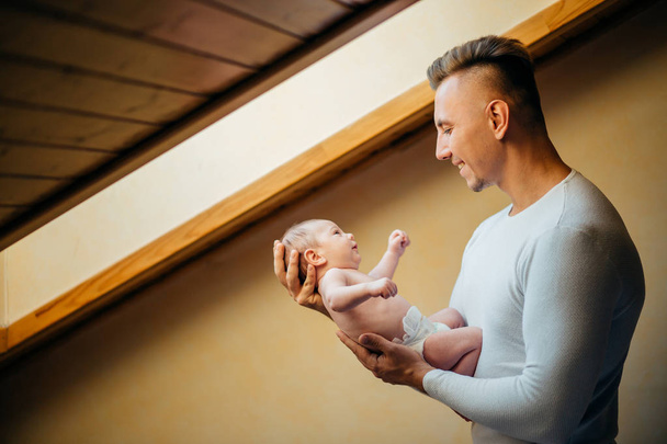 Father Holding Newborn Baby At Home near window - Valokuva, kuva
