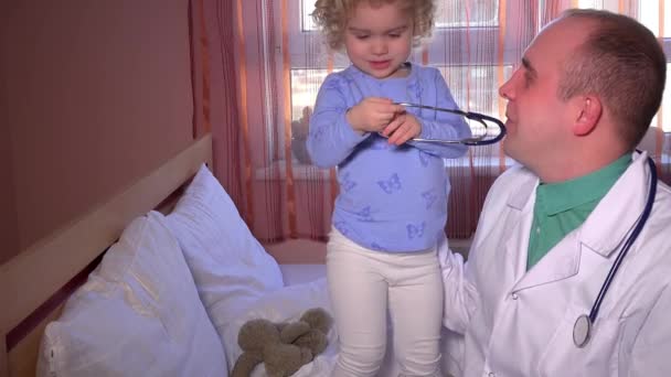 Toddler dziecko podejmuje lekarz stetoskop człowieka. Relacja pacjenta dziewczyna i Medyk - Materiał filmowy, wideo