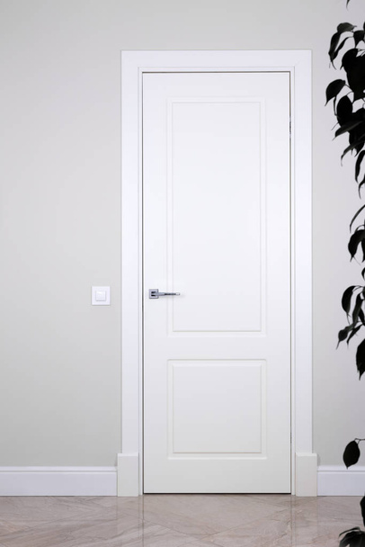 White door and switch on a light gray wall. The bright elements of the interior - Φωτογραφία, εικόνα