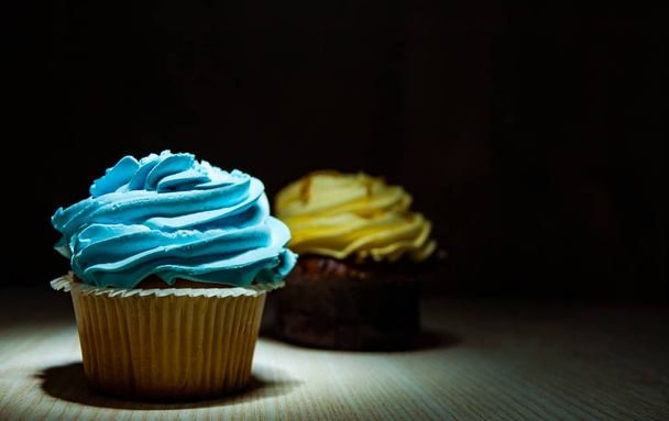 Yummy cupcake with buttercream on wooden table against dark background with copy space. - Zdjęcie, obraz