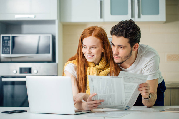 Happy couple at home paying bills with laptop - Photo, Image