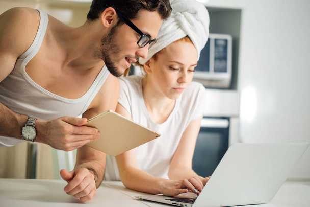 Couple with laptop and tablet in kitchen - Foto, immagini
