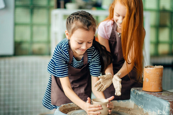 working process with clay potter wheel. Two girls making pottery in studio - Zdjęcie, obraz