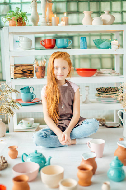 girl wih many cups made from clay sitting in pottery studio - Φωτογραφία, εικόνα