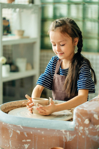 Child sculpts from clay pot. modeling on potter wheel. - Zdjęcie, obraz