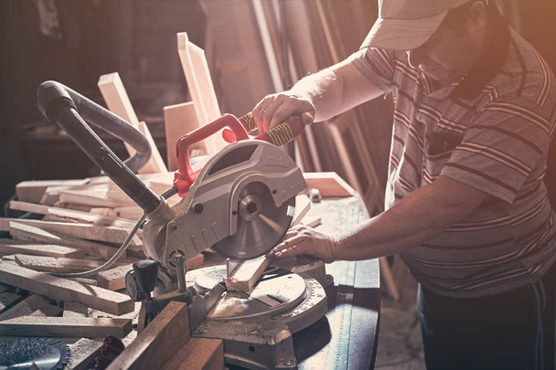 The carpenter cuts the wooden part on the saw. - Fotó, kép