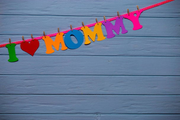 Guirlande avec texte "J'aime maman" de l'alphabet en papier coloré sur un mur en bois bleu
 - Photo, image
