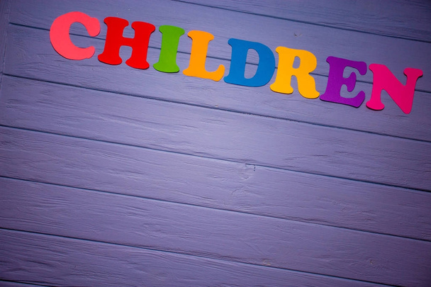 das Wort Kinder mit buntem Papieralphabet auf violettem Holzgrund - Foto, Bild