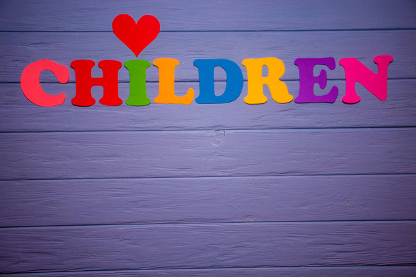 Слово дети с цветным бумажным алфавитом на фиолетовом деревянном фоне
 - Фото, изображение