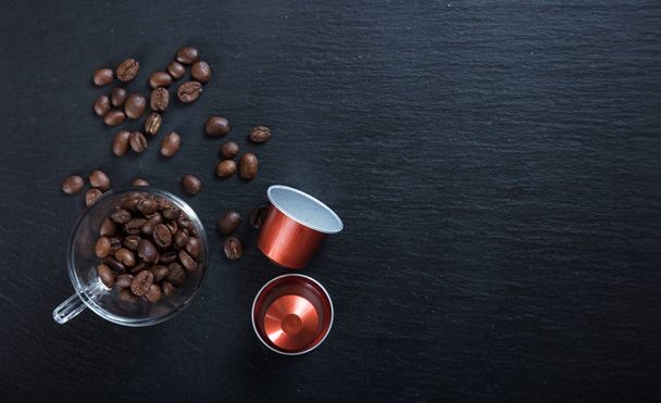 Kapsułki espresso, filiżanki kawy i fasoli na czarnym tle, widok z miejsca kopii z góry - Zdjęcie, obraz