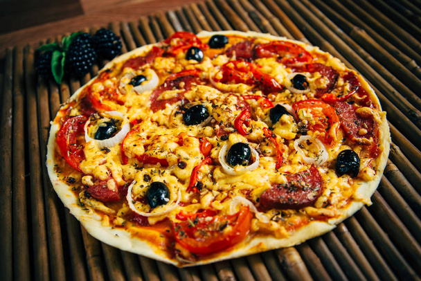Pizza con olive e salumi decorata con frutti di bosco e basilico
 - Foto, immagini