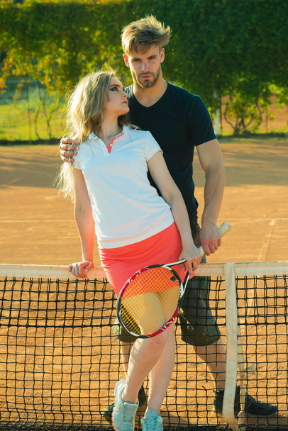 Couple in love stand at tennis net on clay court - Фото, зображення