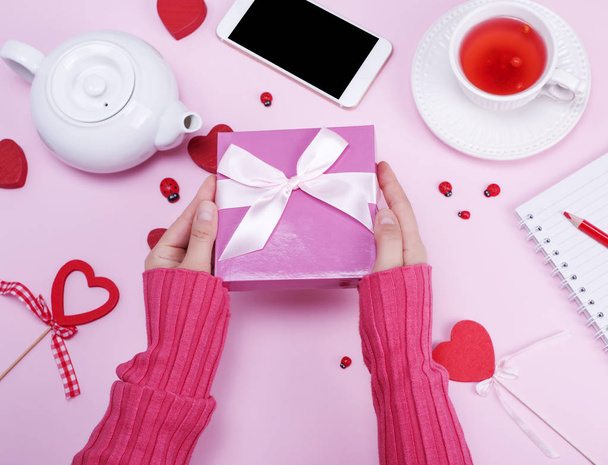 mãos femininas segurar caixa embalada com um arco rosa
 - Foto, Imagem