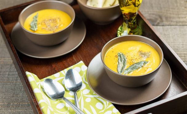 pumpkin soup with sage leaves in brown ceramic soup plate. - Foto, immagini