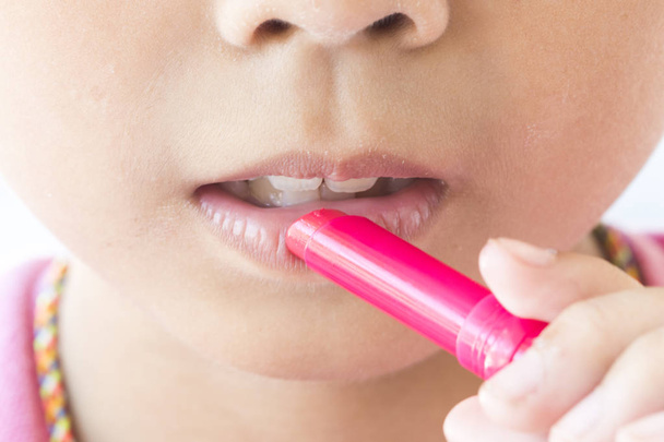 bambini ragazza con rossetto rosa colorato per l'inverno proteggere la bocca secca
 - Foto, immagini