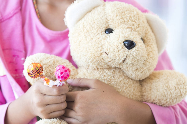 Ruční dívka drží medvídek a držet candy hraje - Fotografie, Obrázek