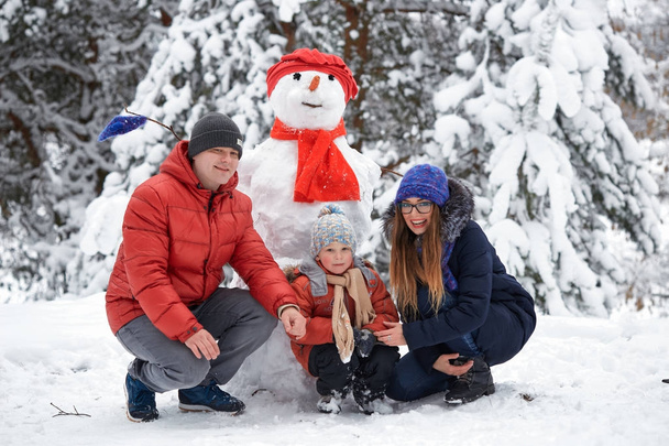 winter fun. a girl, a man and a boy making a snowman. - Photo, Image