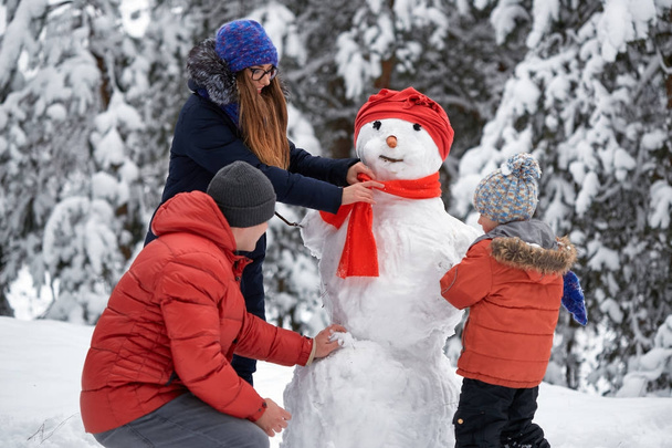 Diversão de inverno. uma menina, um homem e um menino fazendo um boneco de neve
. - Foto, Imagem