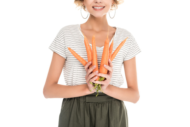 recortado disparo de sonriente joven sosteniendo zanahorias maduras aisladas en blanco
 - Foto, Imagen