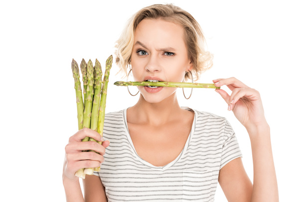 portrait of young woman biting raw asparagus in hands isolated on white - Photo, Image