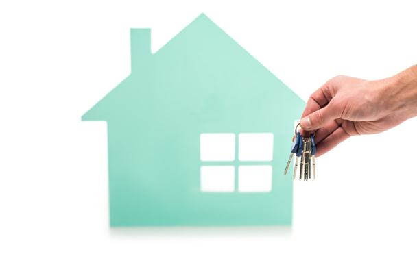 обрезанный снимок мужской руки с ключами и модель дома изолированы на белом
 - Фото, изображение