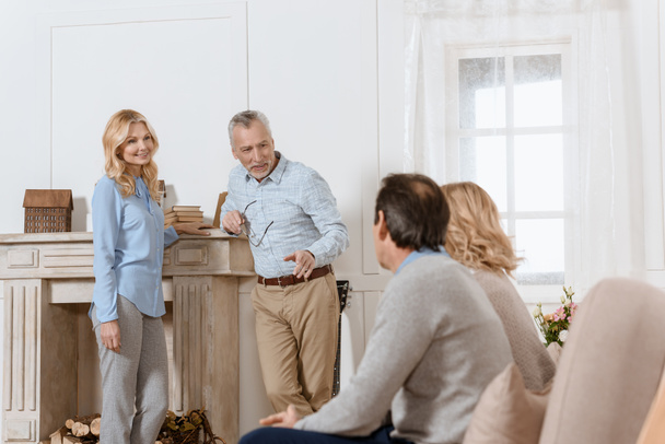 Старшие мужчины и женщины ведут дружескую беседу в светлой уютной комнате
 - Фото, изображение