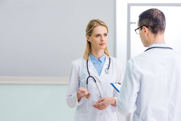 two doctors in white coats discussing diagnosis in clinic - Photo, image