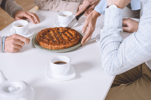 cropped image of woman cutting pie on table while friends sitting   - Photo, Image