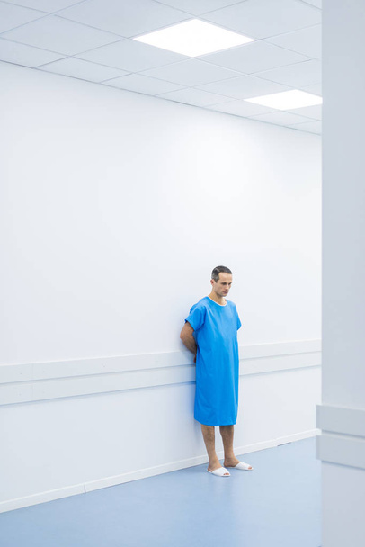 male patient in medical gown standing at wall in hospital  - Fotoğraf, Görsel
