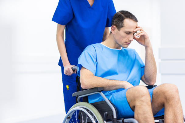 surgeon and upset patient in wheelchair in hospital corridor  - 写真・画像
