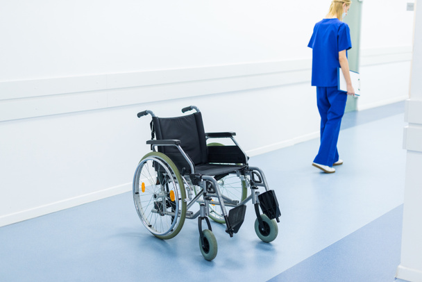 vrouwelijke chirurg in ziekenhuis gang, rolstoel op voorgrond - Foto, afbeelding