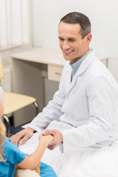 smiling doctor holding hands with kid patient  - Photo, Image