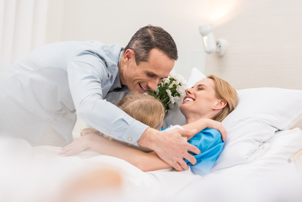 daughter and father hugging mother at hospital - Valokuva, kuva