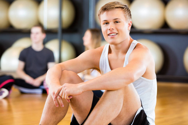 Selbstbewusster Mann sitzt im Fitnessstudio - Foto, Bild