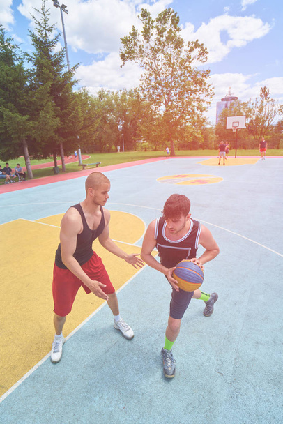 Couple of guys playing basketball outside      - 写真・画像
