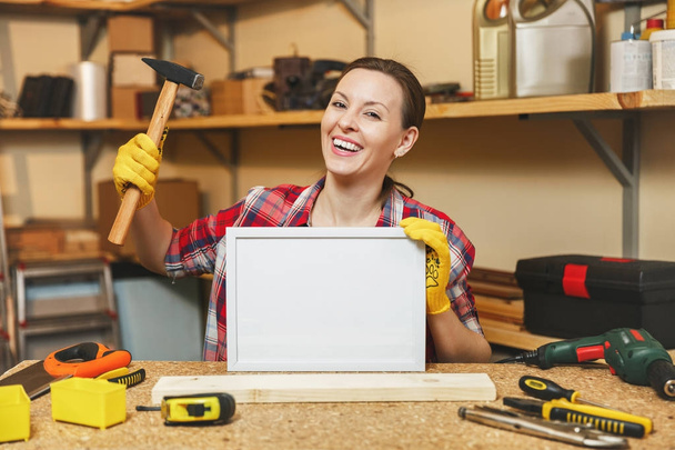 Mujer joven con camisa a cuadros, guantes amarillos trabajando en carpintería w
 - Foto, Imagen