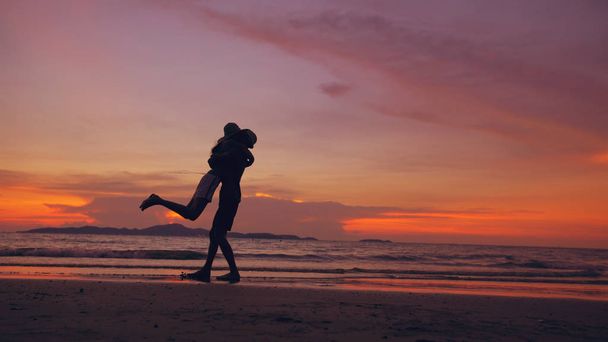 Siluetti onnellinen rakastava pari tavata ja pelata rannalla auringonlaskun valtameren rannalla
 - Valokuva, kuva