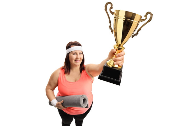 Overweight woman with an exercise mat and a trophy - 写真・画像