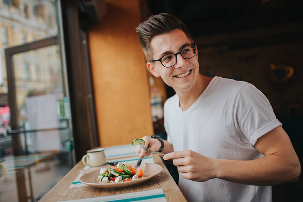 The Young caucasian man with glasses eating a healthy salad. - Fotografie, Obrázek