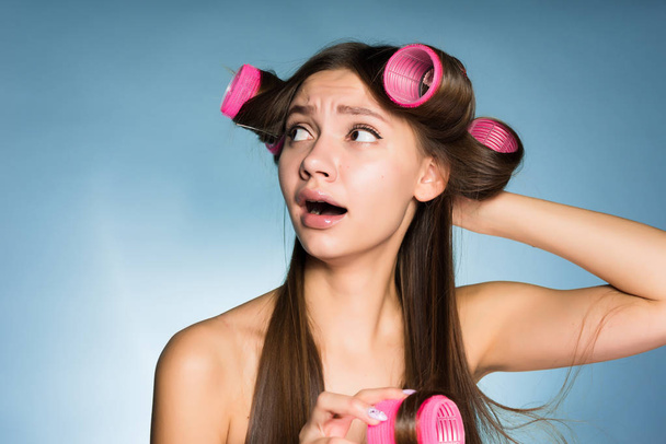 sad young girl can not make a fashionable hairstyle with curlers - Valokuva, kuva