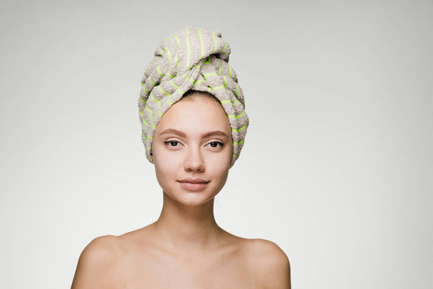 confident beautiful young girl with clean skin, with a green towel on her head looking at the camera - Fotografie, Obrázek