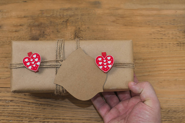 zwei rote Herzen auf Clips an einem Seil der Geschenkschachtel in braunes Bastelpapier gewickelt.   - Foto, Bild