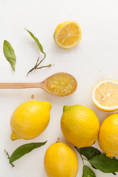 Fresh lemons with leaves and chopped lemons and sugar in a bowl on a white background. - Foto, Imagem