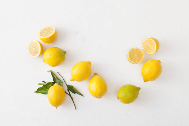 A bunch of lemons with leaves and sliced lemons on a white concrete background. - Foto, immagini
