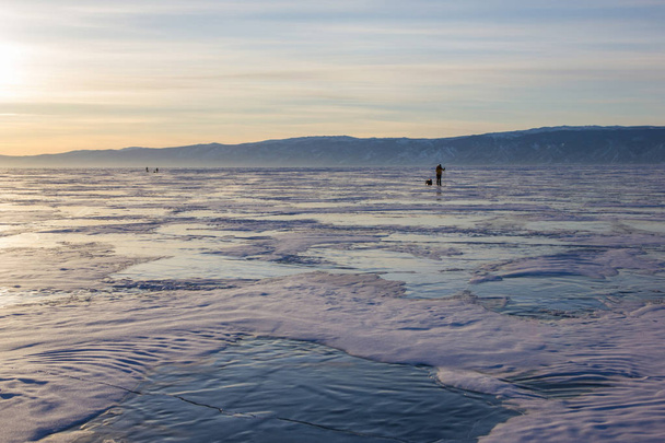 male hiker with backpack walking on ice water surface against hills on shore,russia, lake baikal    - Zdjęcie, obraz