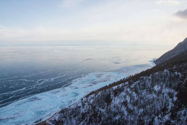 氷の水表面、ロシア、バイカル湖に対して木と丘の斜面  - 写真・画像