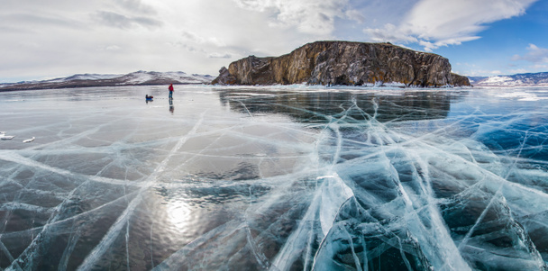 randonneur mâle avec sac à dos debout sur la surface de l'eau glacée contre la formation de roche sur le rivage, la Russie, le lac baïkal
  - Photo, image