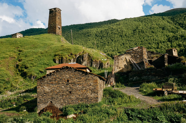 Nézd a füves terület a régi, elöregedett, vidéki épületek és hegyek a háttérben, Ushguli, svaneti, Grúzia    - Fotó, kép